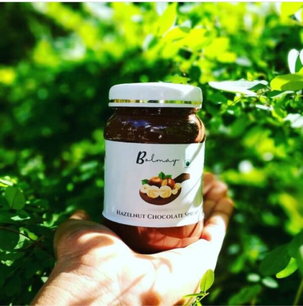 Photo of Bolmay hazelnut chocolate spread in hand with greenery background